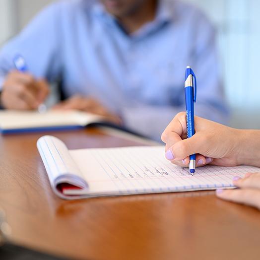 a hand holding a pen writing on notepad