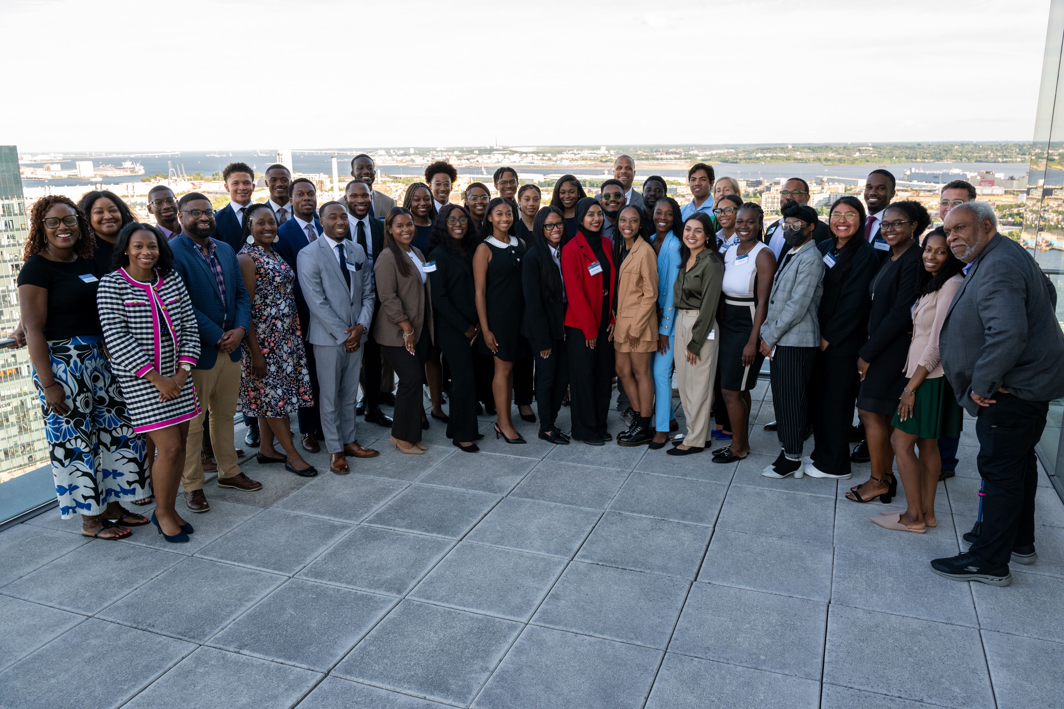 Large group of people standing outside on a terrace in a group all smiling for a photo