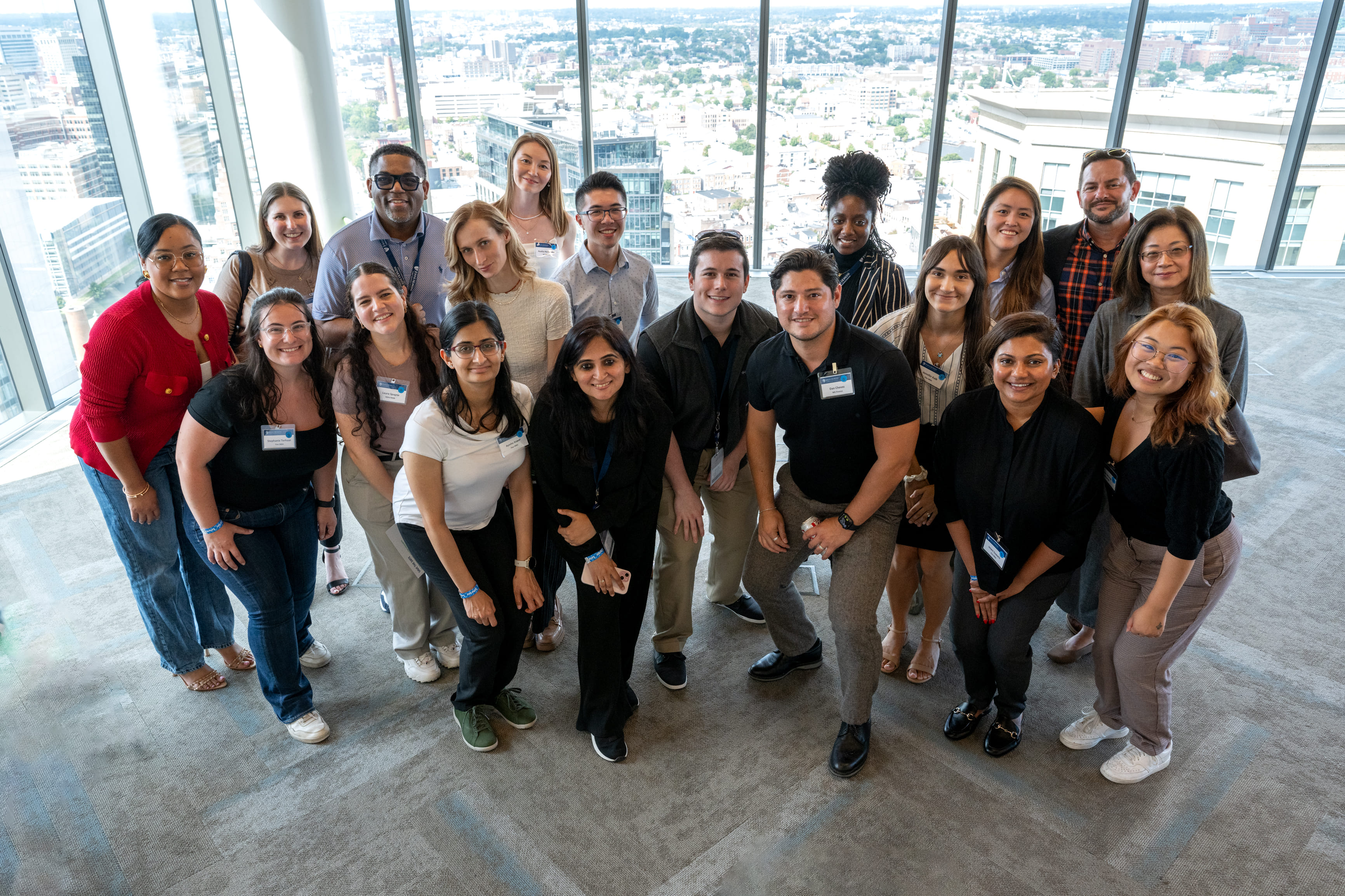 group of people smiling for a photo in front of large windows