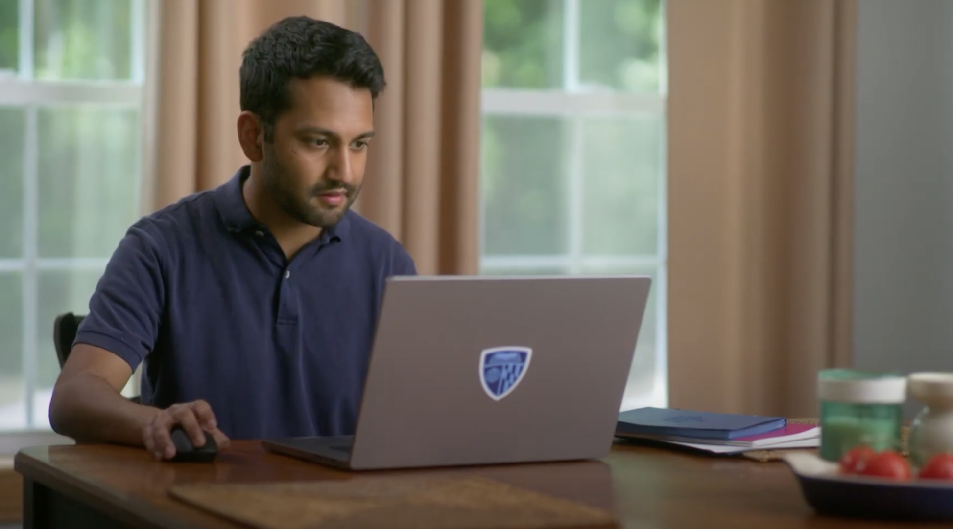 person sitting at table inside a house on a laptop