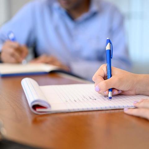 a hand holding a pen writing on notepad