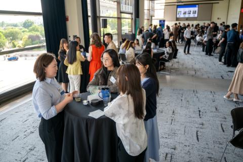 groups of people standing at tables in a large event room, all speaking to each other