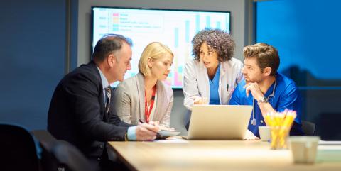 four people at a table looking at a computer