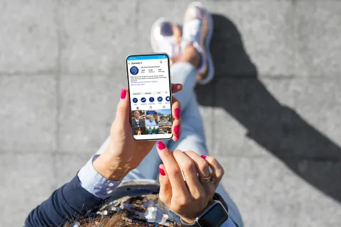 person on their phone from a birds eye view and the phone has carey business school's instagram up