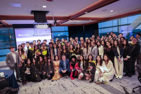 large group of students and faculty posing for photo. some in graduation regalia