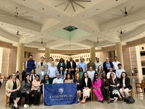 group of students posing together for a photo with a carey business school flag 