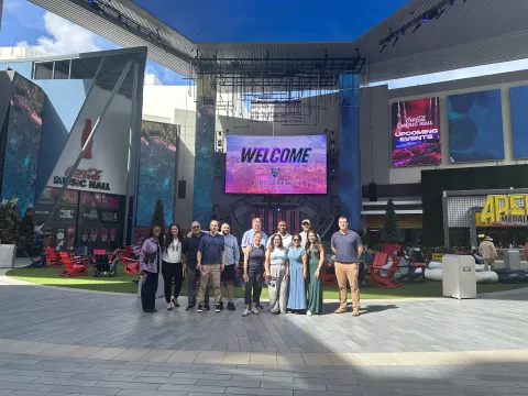 students smiling for a photo with a screen in the back that says welcome johns hopkins carey business school
