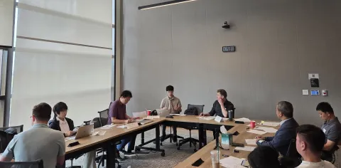 people sitting in a room around a U-shaped table