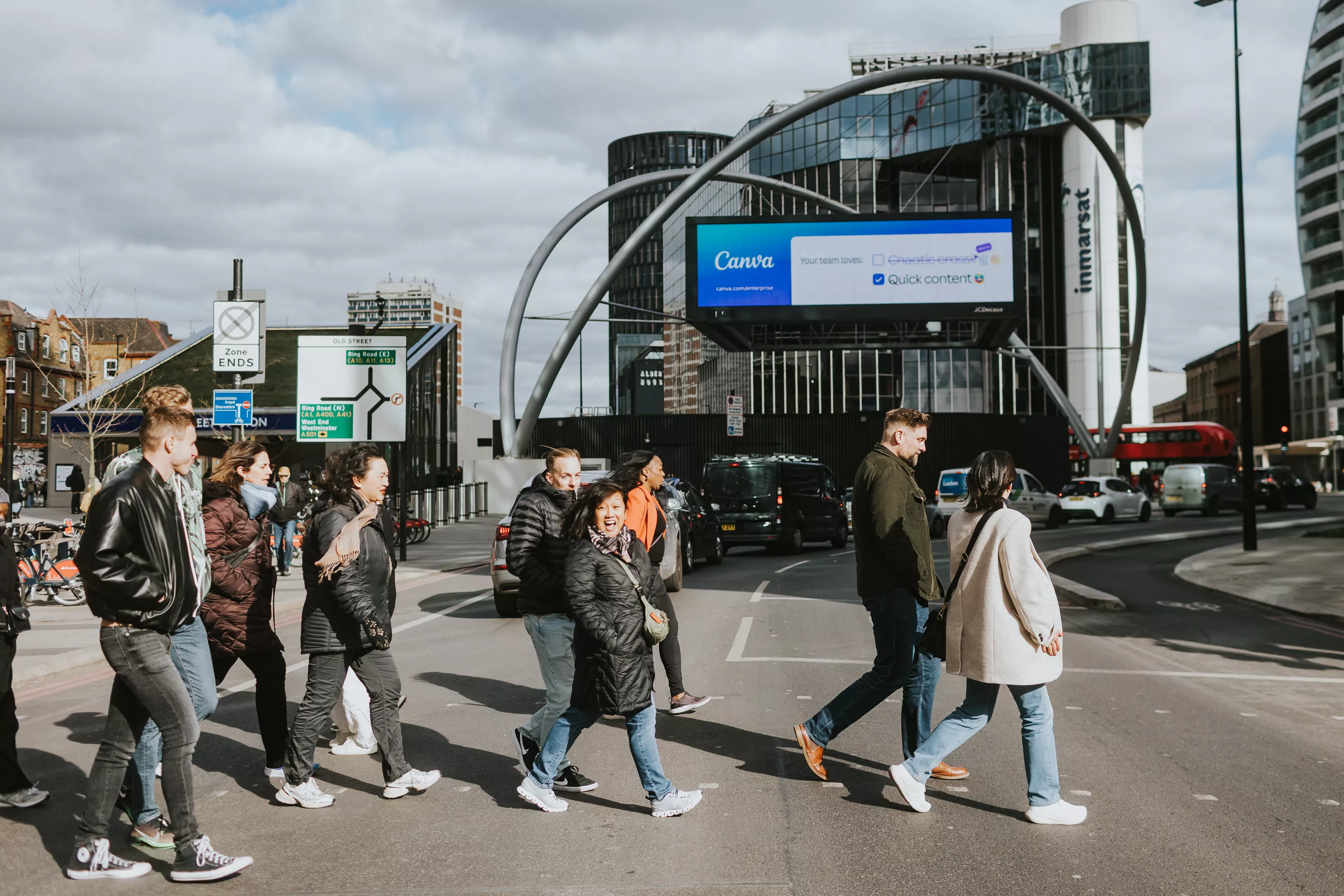 group of people crossing the street, only one person is looking at the camera and smiling