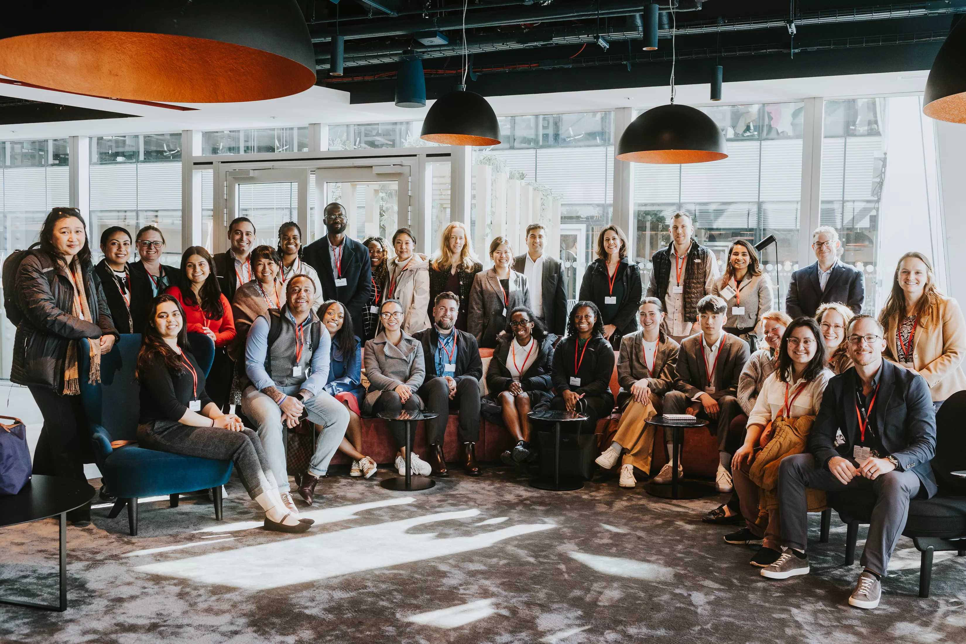 group photo of people smiling, standing and sitting inside a building