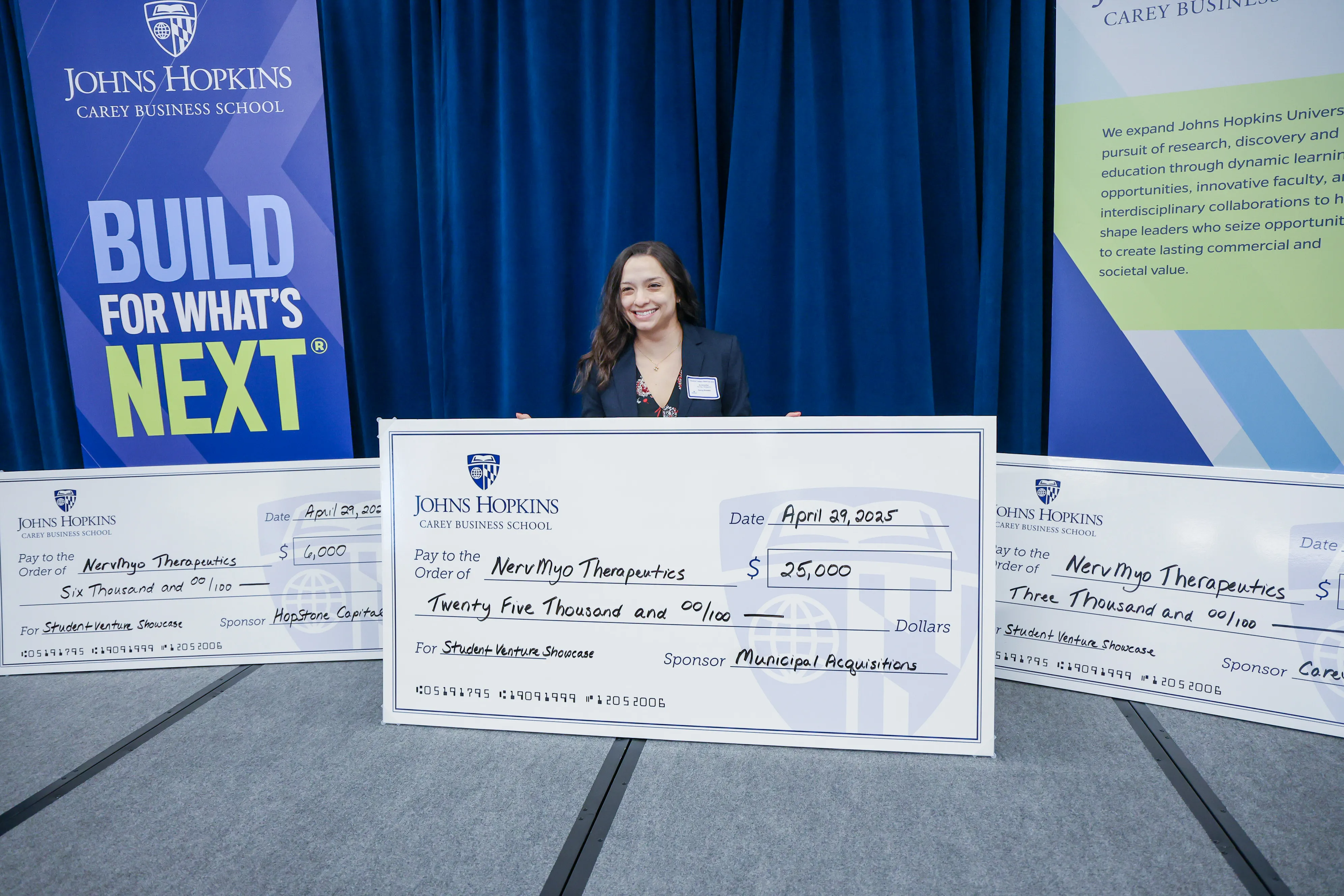one person posing for photo, holding large check with two other large checks next to them