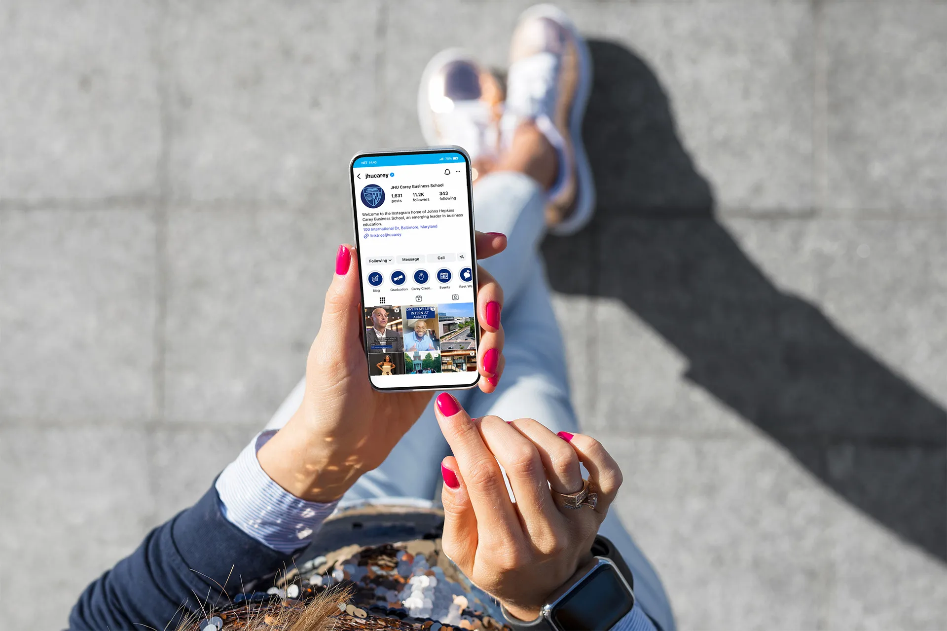 person on their phone from a birds eye view and the phone has carey business school's instagram up