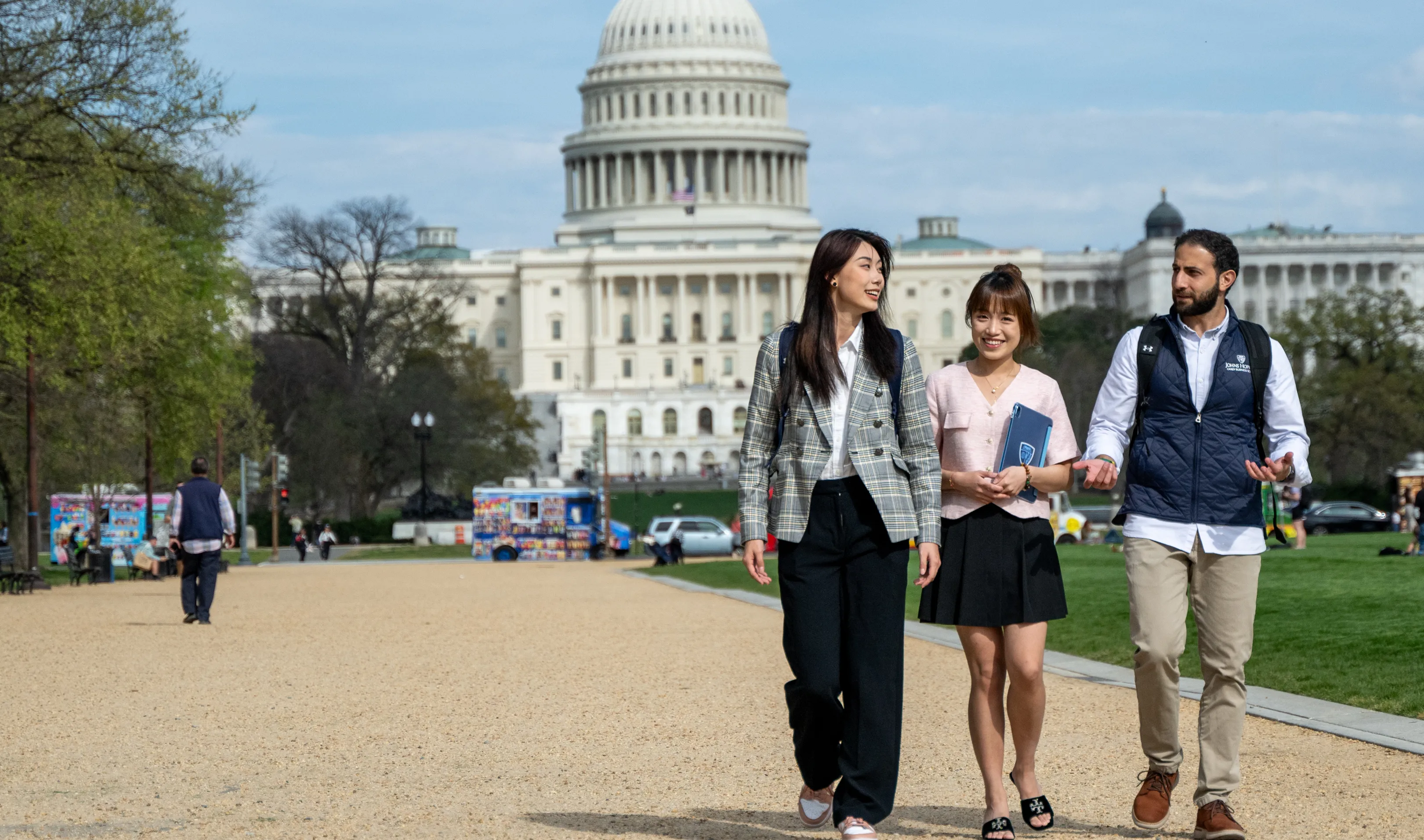 three people walking outside on a path in front of the capitol building