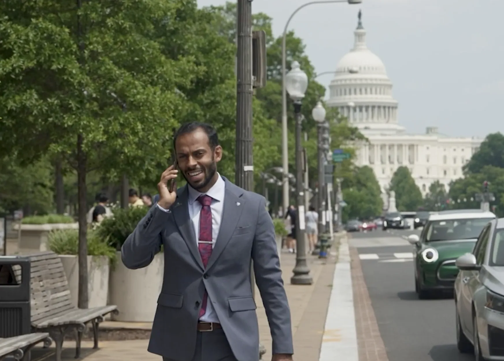 person walking outside on phone in business attire, Washington, D.C. capital building in the background