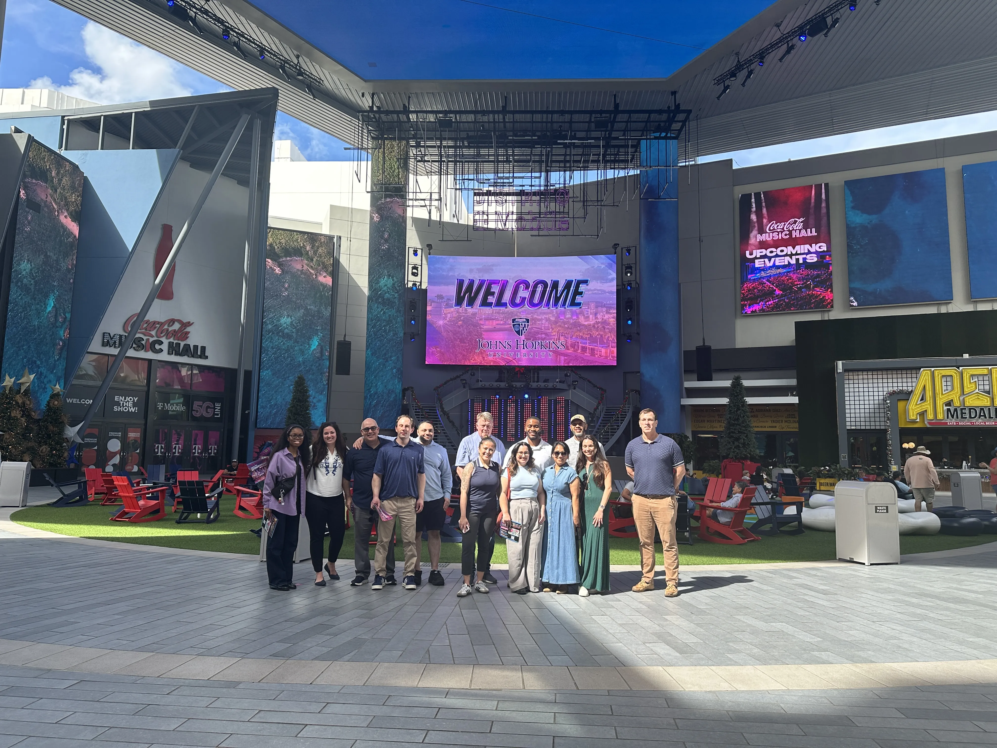 students smiling for a photo with a screen in the back that says welcome johns hopkins carey business school