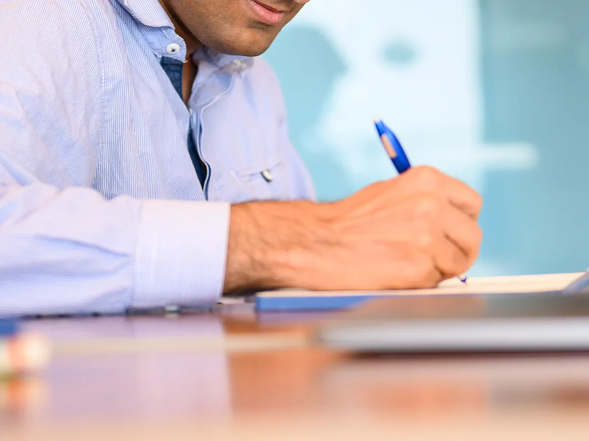 person writing in a notepad with a pen
