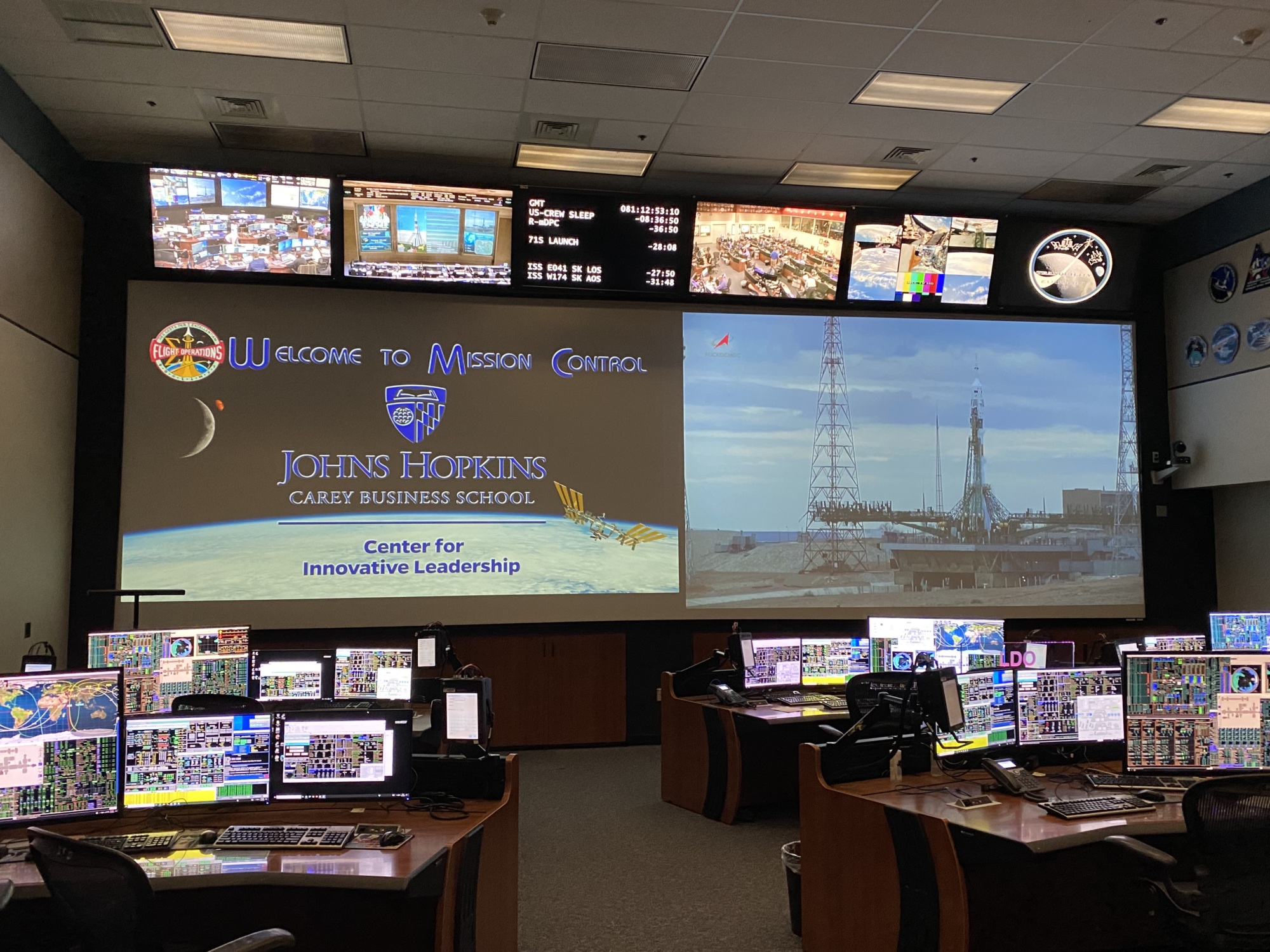 large screen in nasa mission control room with computers