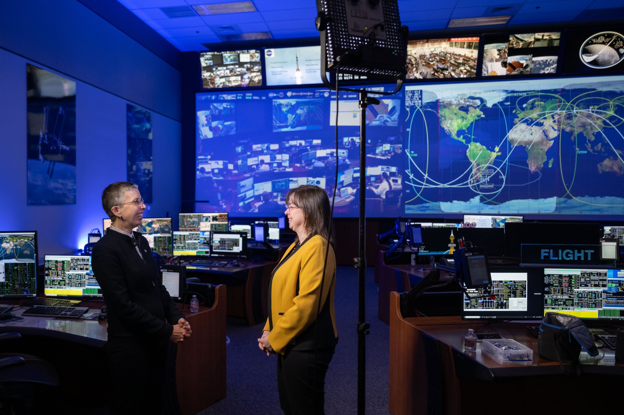 two people talking in front of a control screen