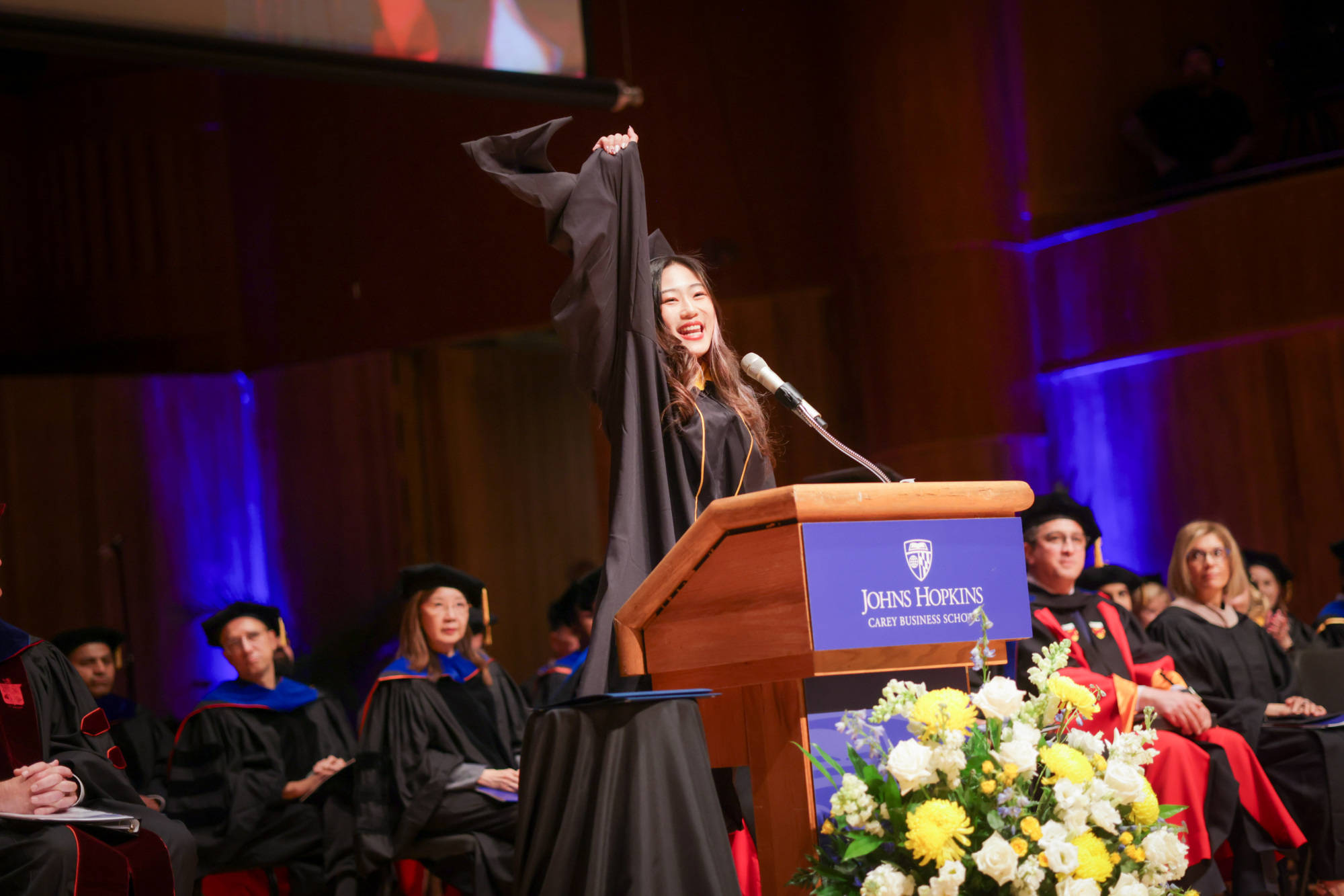 woman standing at podium speaking with her hand in the air