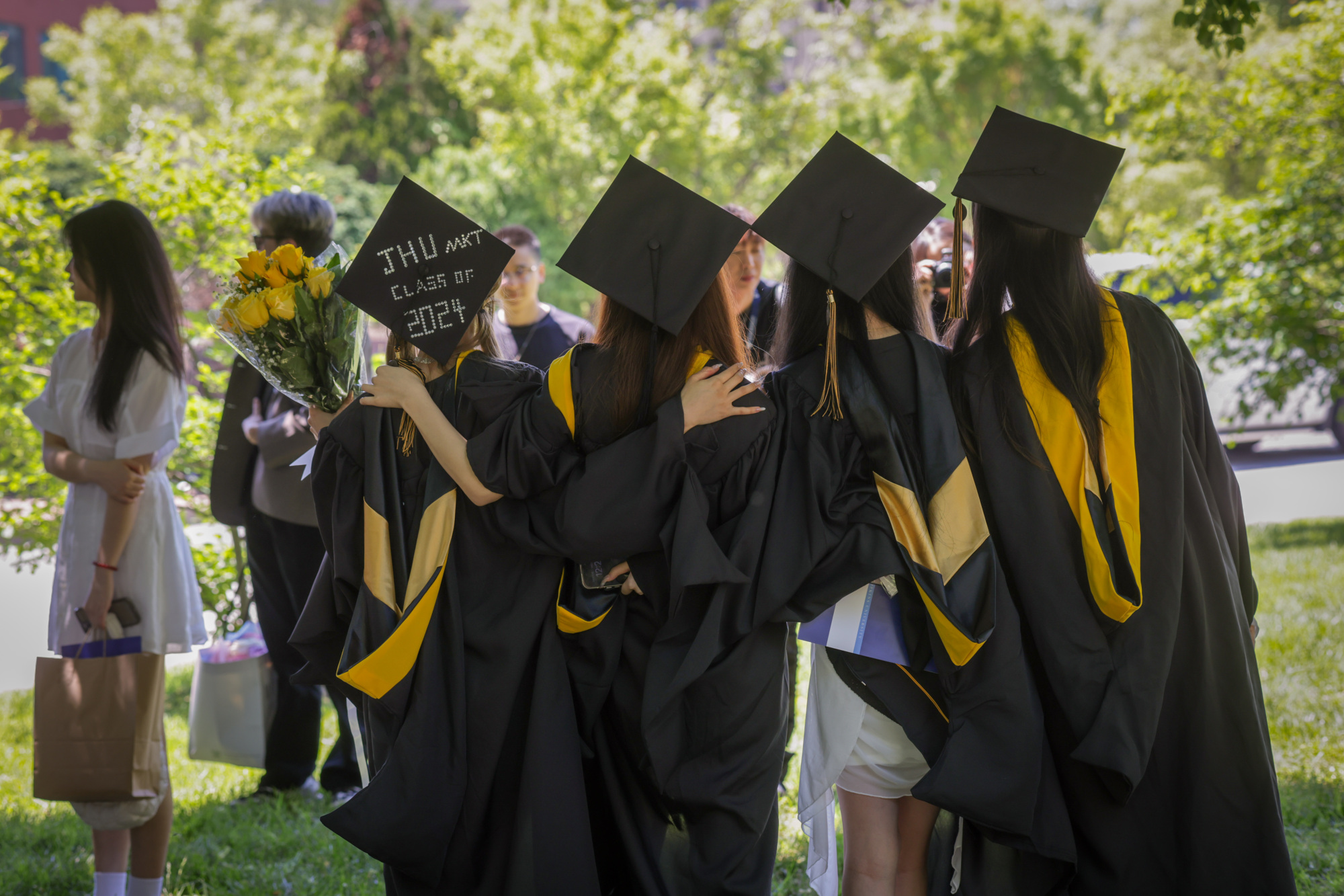 four people standing with their graduation caps towards the camera
