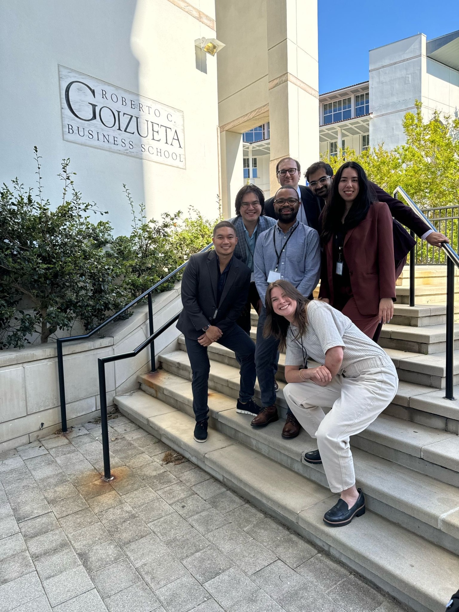 seven people standing on stairs outside posing for photo