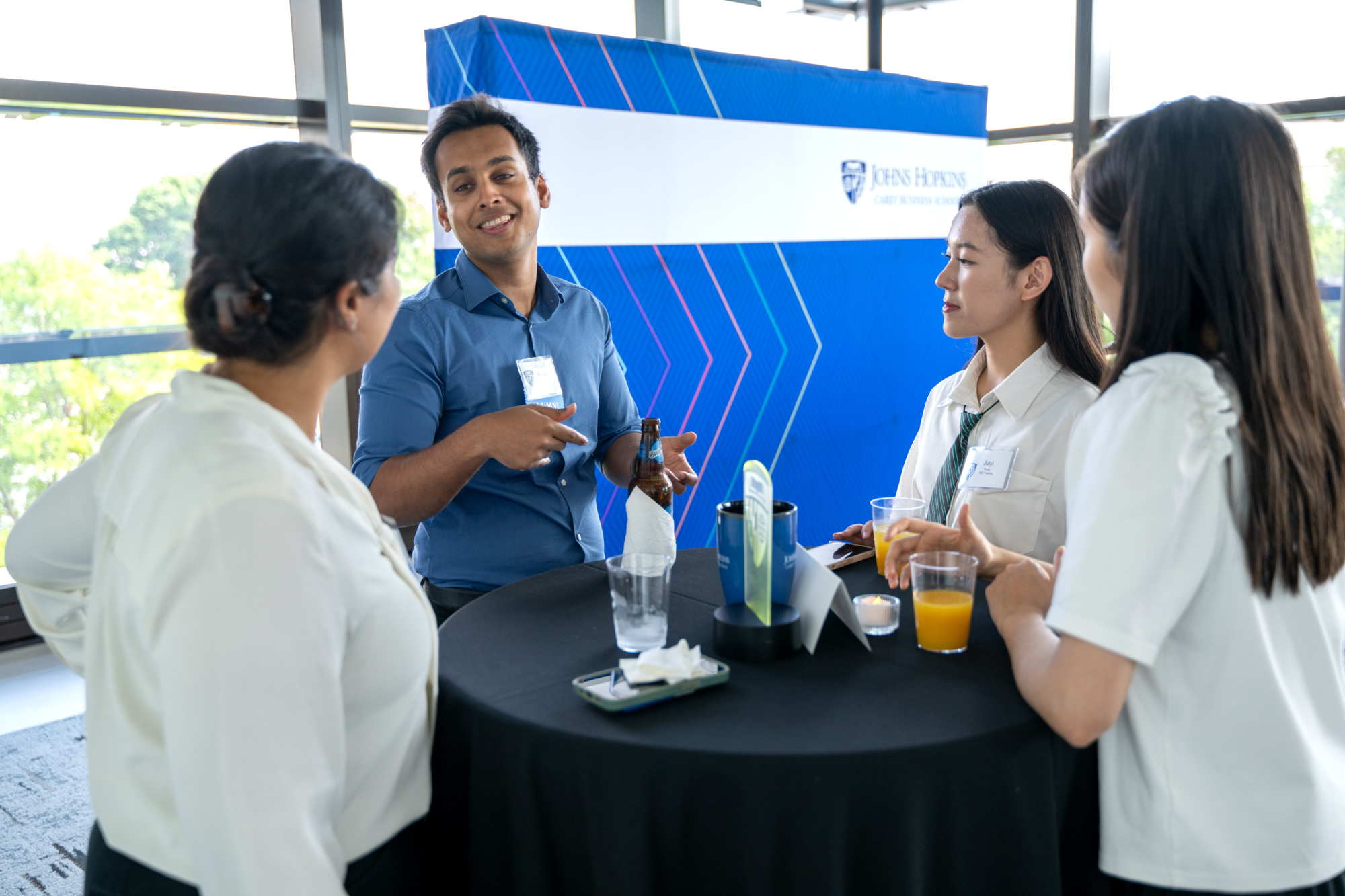 four people standing around a high-top table talking