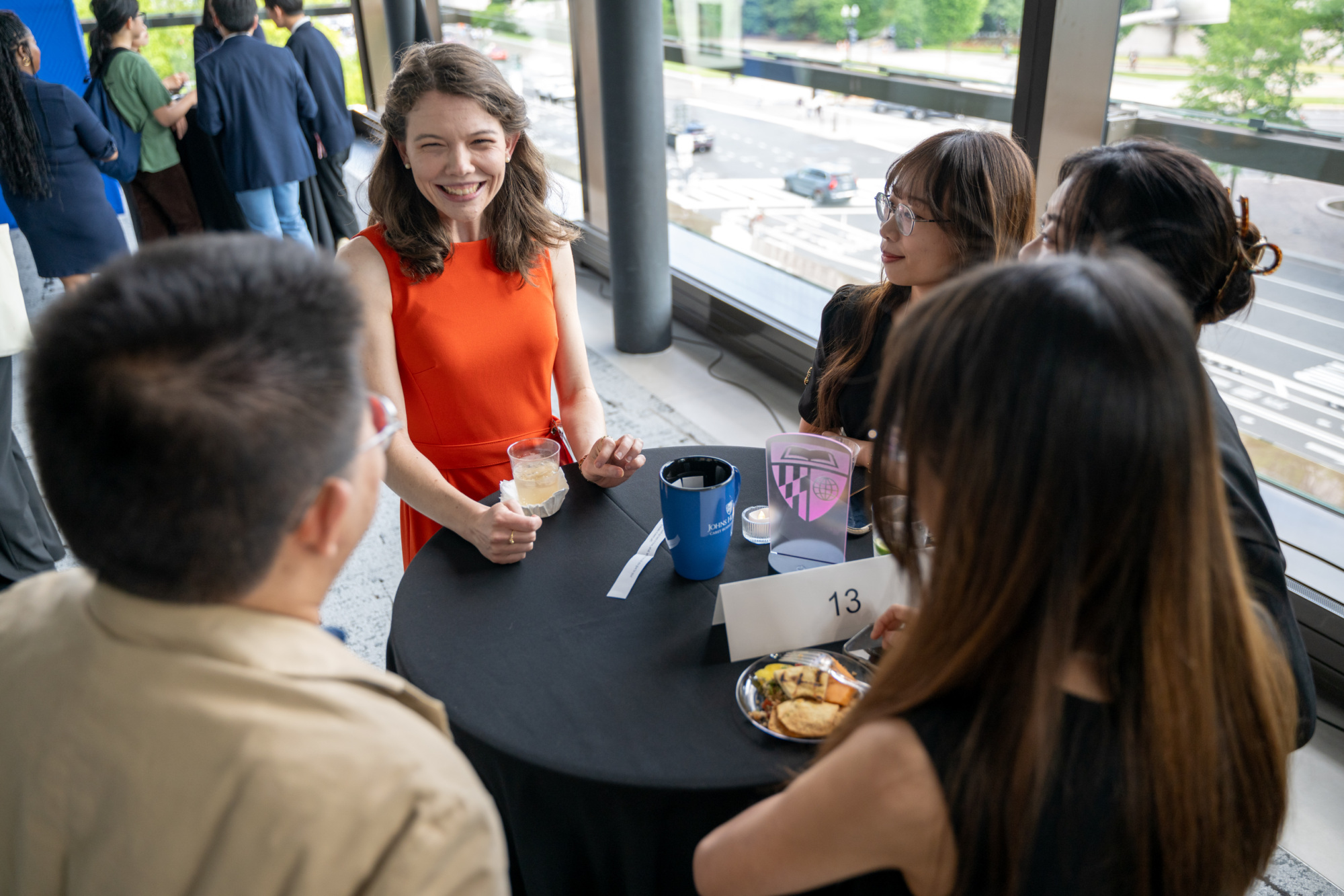 five people standing around a table talking. people are smiling