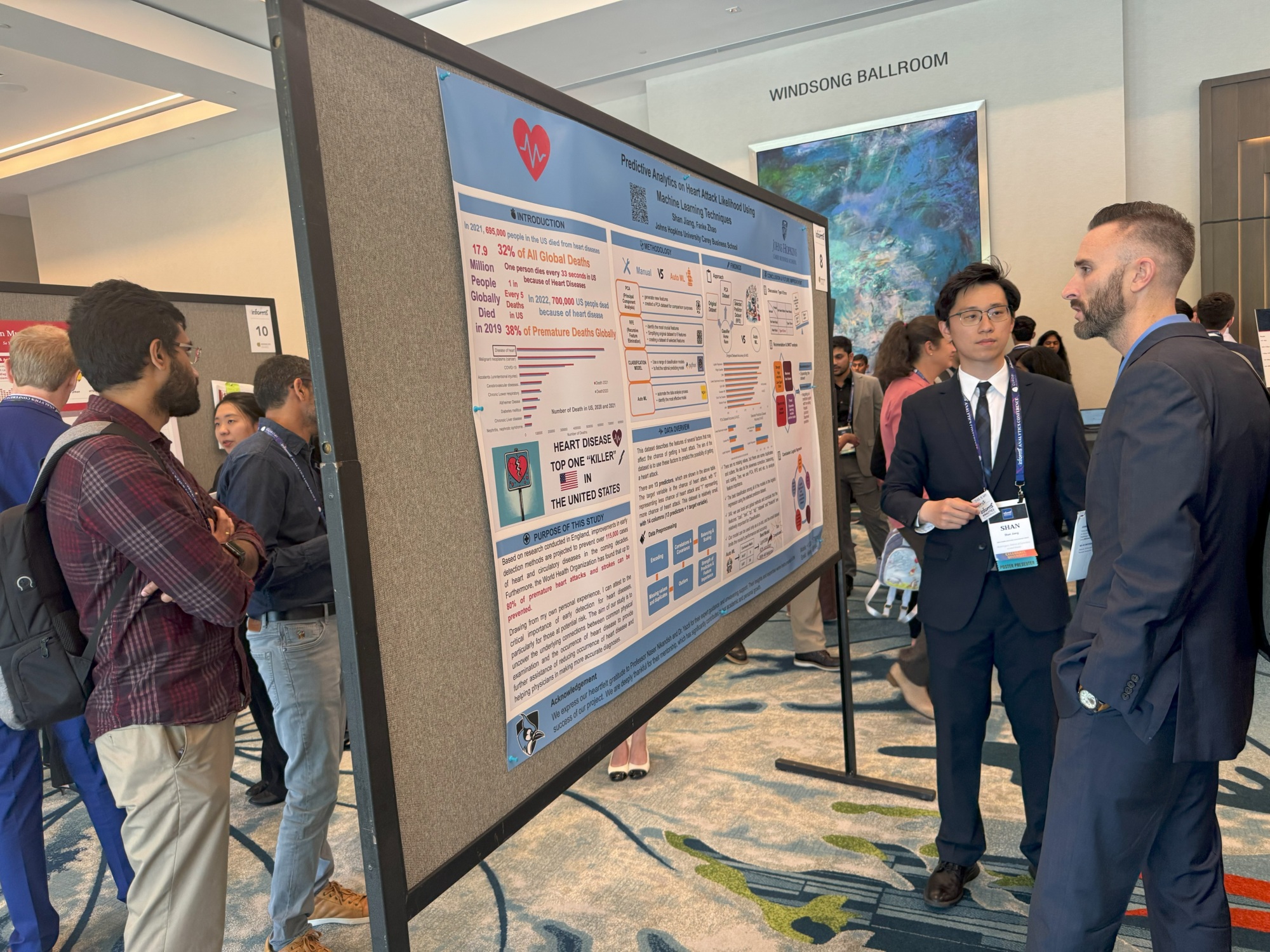 person speaking to another person in front of a large poster board