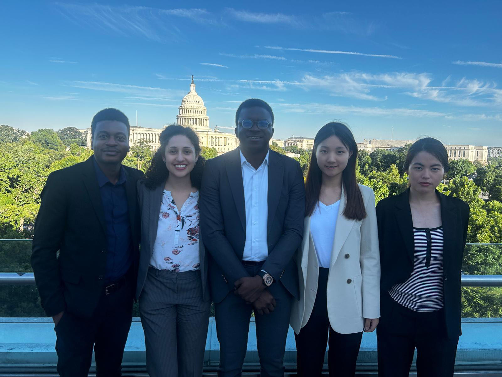 five people standing together for a photo with the capitol building in washington, d.c.