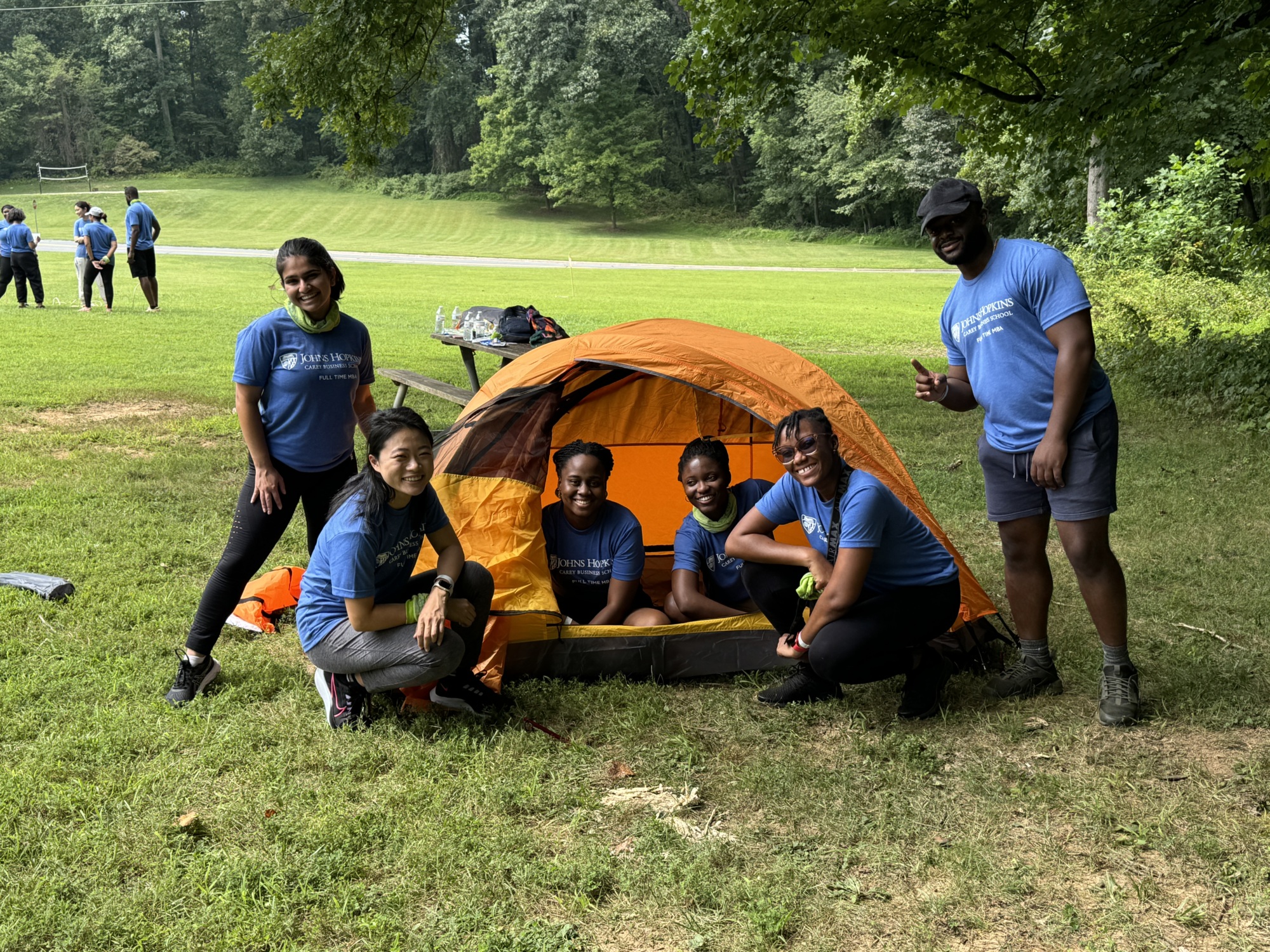 group photo of people smiling. a few people are kneeling down in an unzipped tent