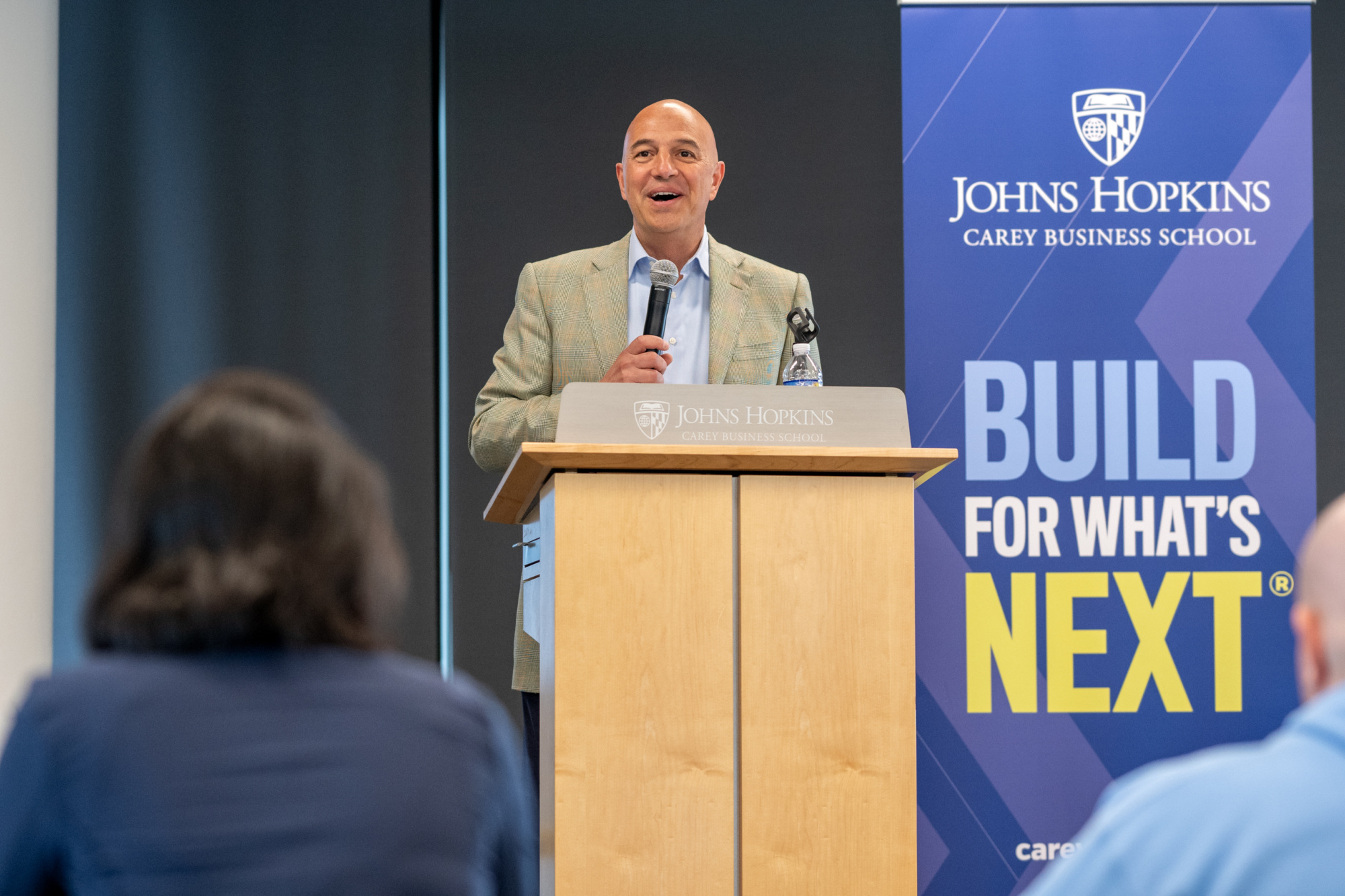 one person standing at podium speaking with a microphone in hand