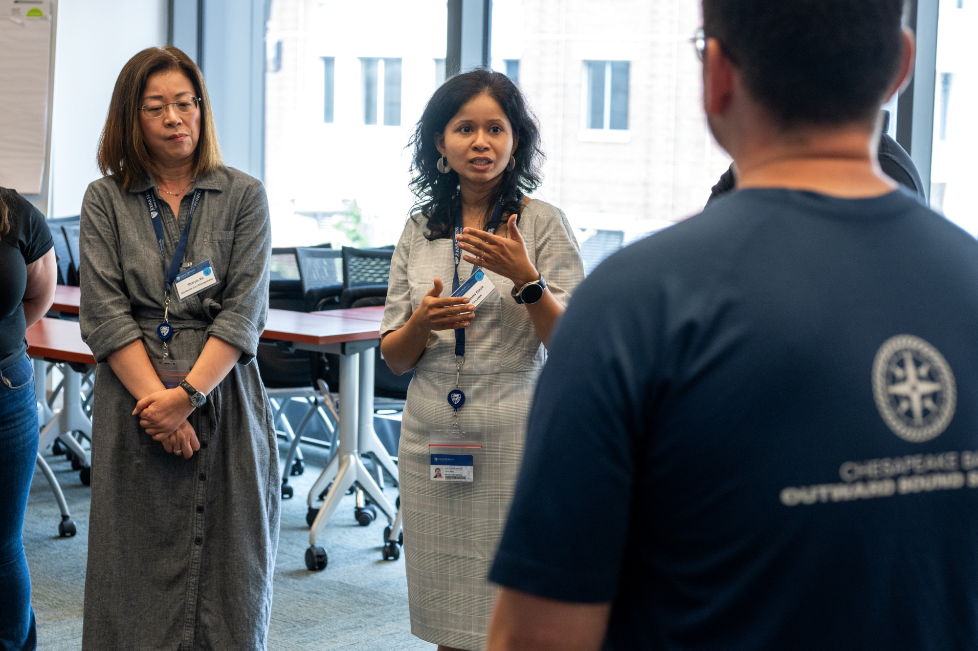 three people standing listening to one person speak. using their hands