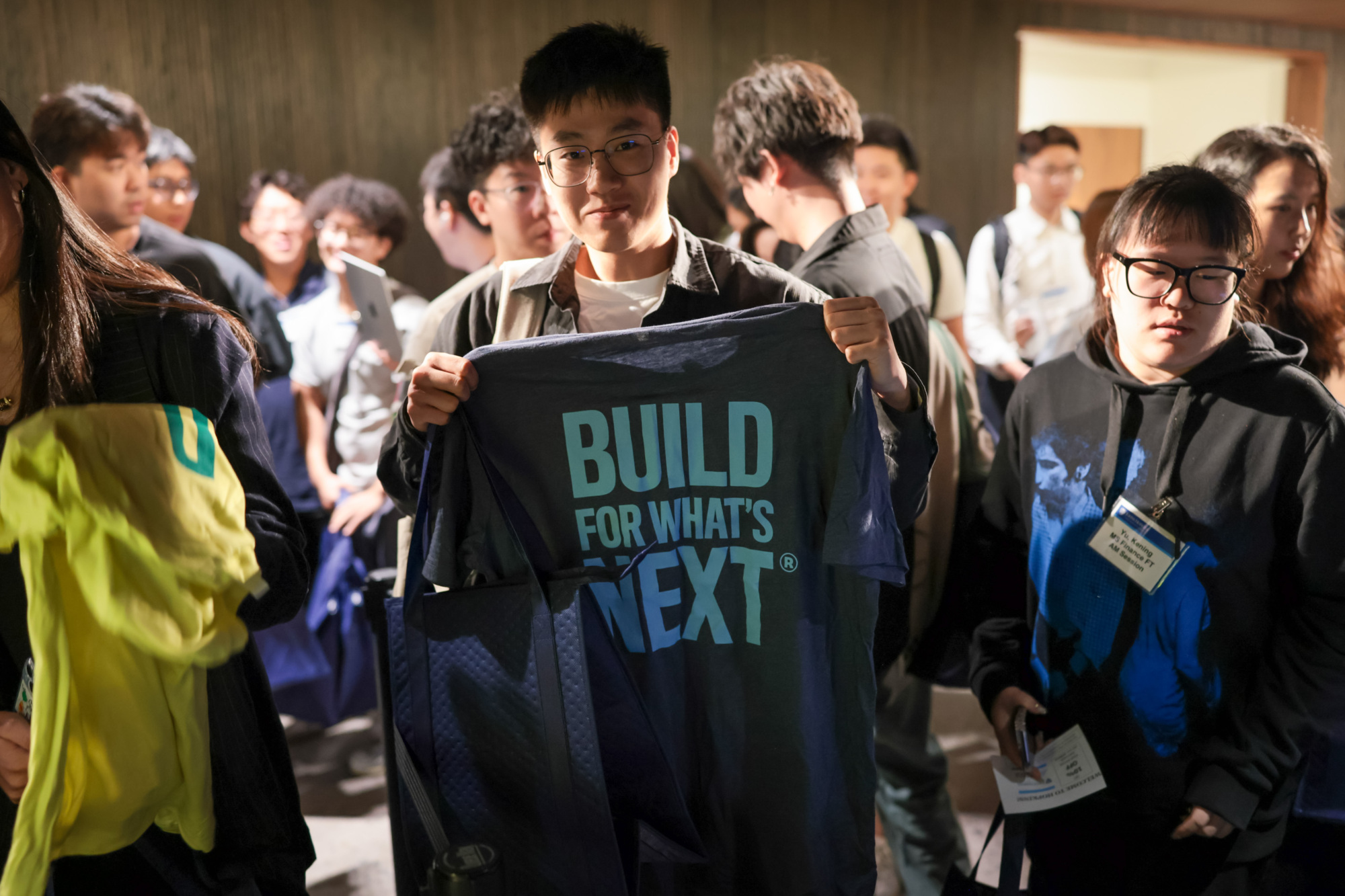 person holding a t shirt that says "build for what's next"