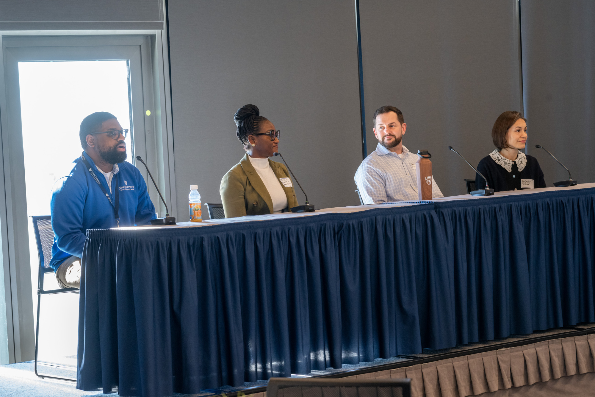 four people sitting at a panel on stage