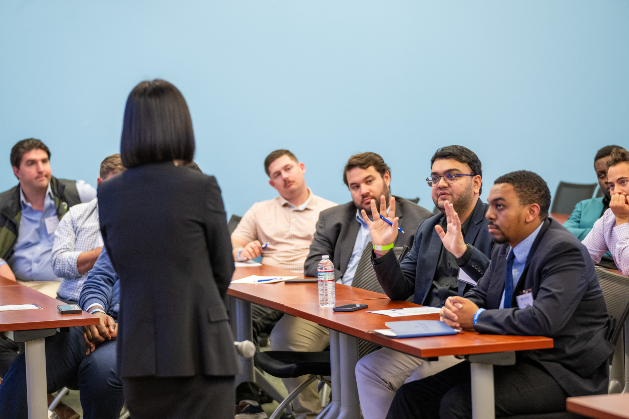 people sitting at table, once person speaking to a person standing