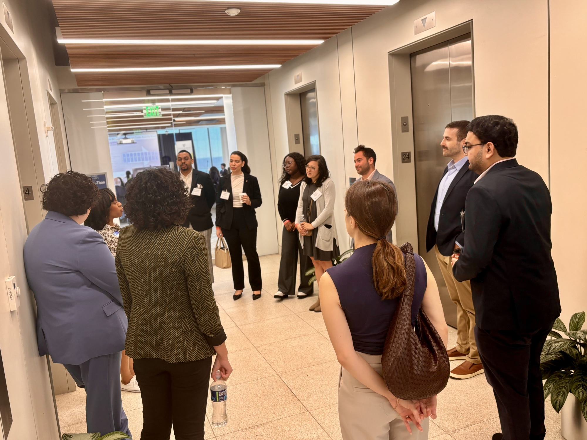 people standing in a circle listening to one person present in a hallway