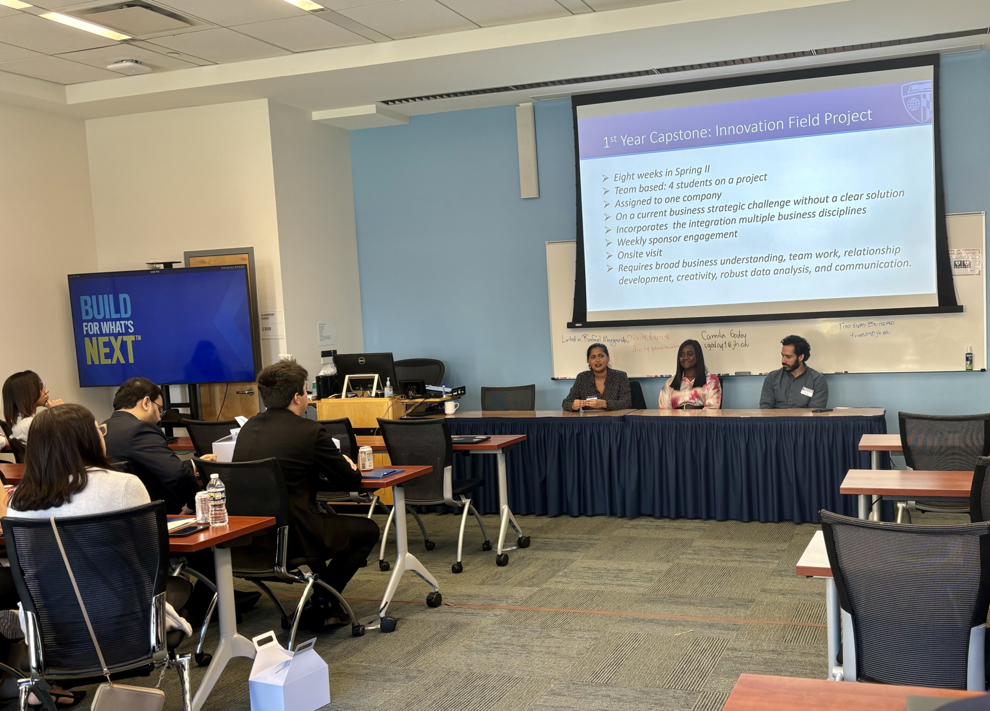 people sitting at a panel in the front of a classroom speaking to people at desks