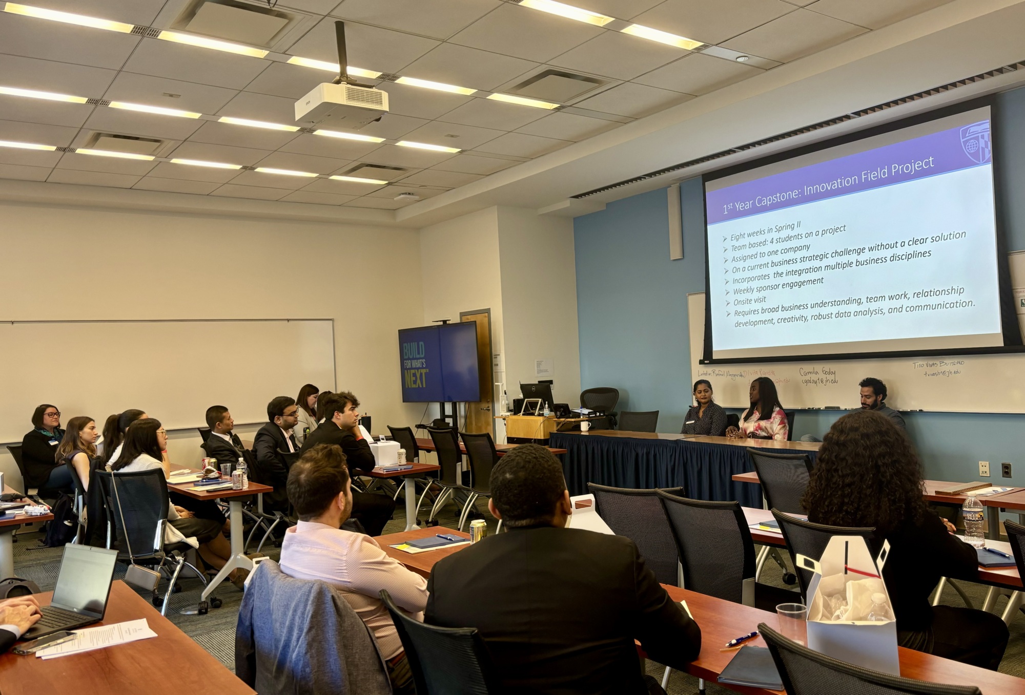 people sitting at a panel in the front of a classroom speaking to people at desks