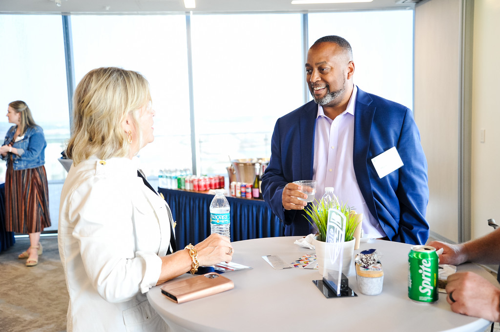 two people in conversation standing around a circle high top table