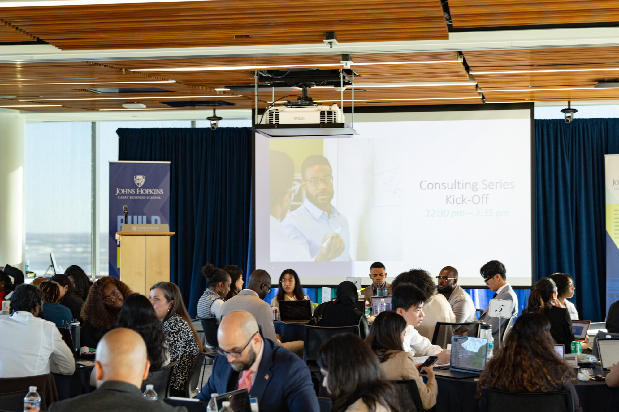 people sitting at tables talking to each other in a large conference room