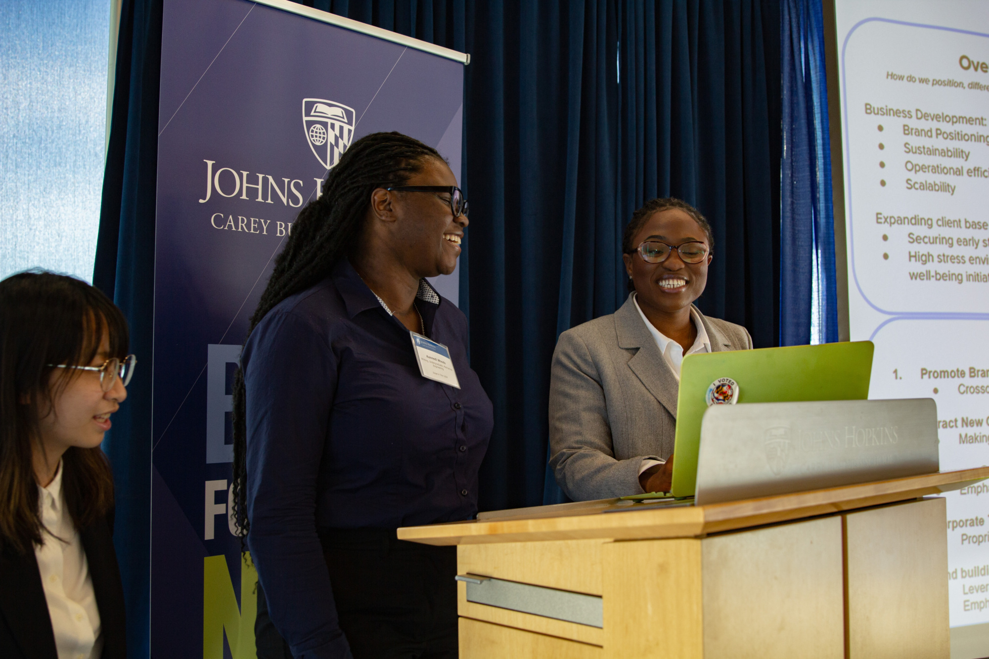 three people standing at a podium smiling