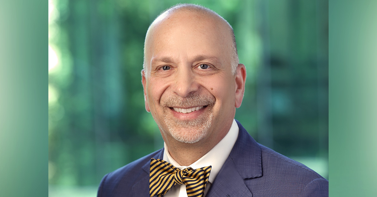 headshot of a person smiling with a suit and bowtie on